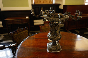 Ornate antique candelabra on a polished wooden table in a classic interior, a Photo by AS photostudio