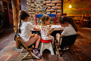 Young children engaging in creative activities around a small table in a colorf, a Photo by AS photostudio