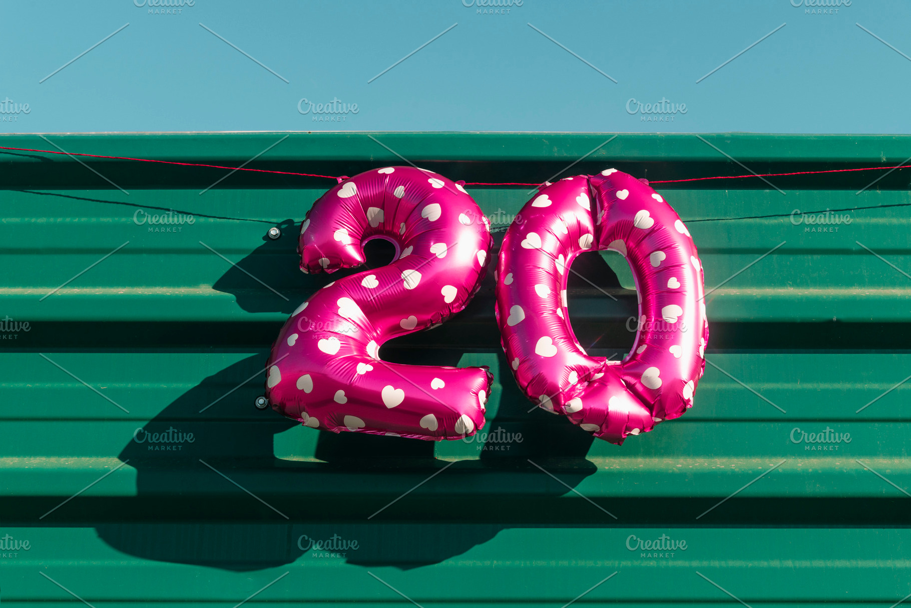 the number 20 displayed with pink balloons, a Photo by Nito