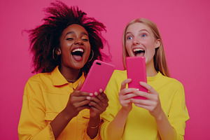 Excited young women using smartphone, a Photo by Pavel_design
