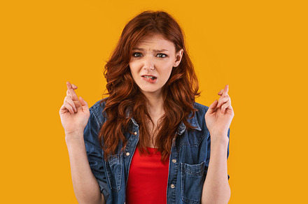Student Girl Keeping Fingers Crossed, a Background Photo by Prostock-Studio