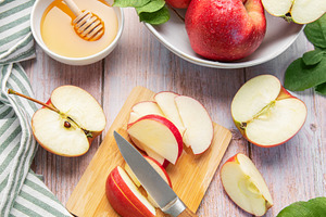 Red apples, honey, and knife on cutting board, a Food & Drink Photo by Olena Rudo