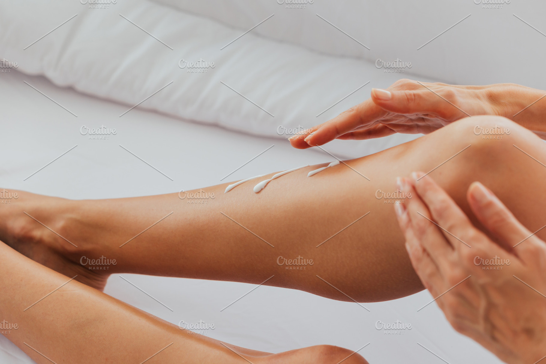 Woman applying cream on legs on bed stock photo containing woman and legs, a Beauty & Fashion Photo by Twinster Photo