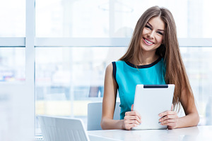 Woman using tablet computer in cafe containing tablet, computer, and coffee