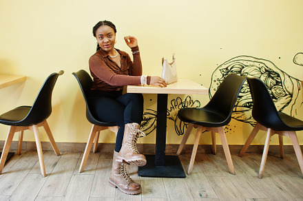 African american woman in brown shirt and black pants sit in caf, a Beauty & Fashion Photo by AS photostudio