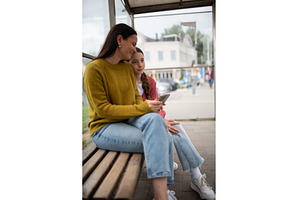Woman and teenage girl waiting at, a Person Photo by HalfPoint