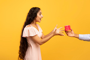 Holiday celebration concept. Male hand holding and giving wrapped gift box to s, a Photo by Prostock-Studio