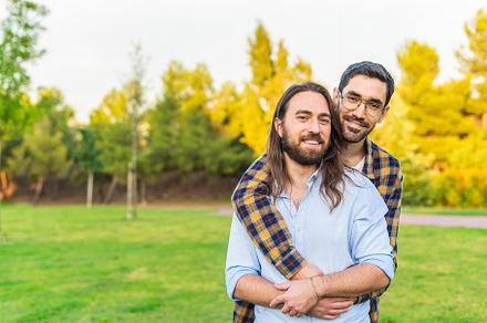 A gay couple looking at camera hugging in the park, a Person Photo by Iván Moreno STOCK PHOTO
