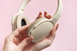 Woman holding wireless headphones on pink background, a Technology Photo by Olena Rudo
