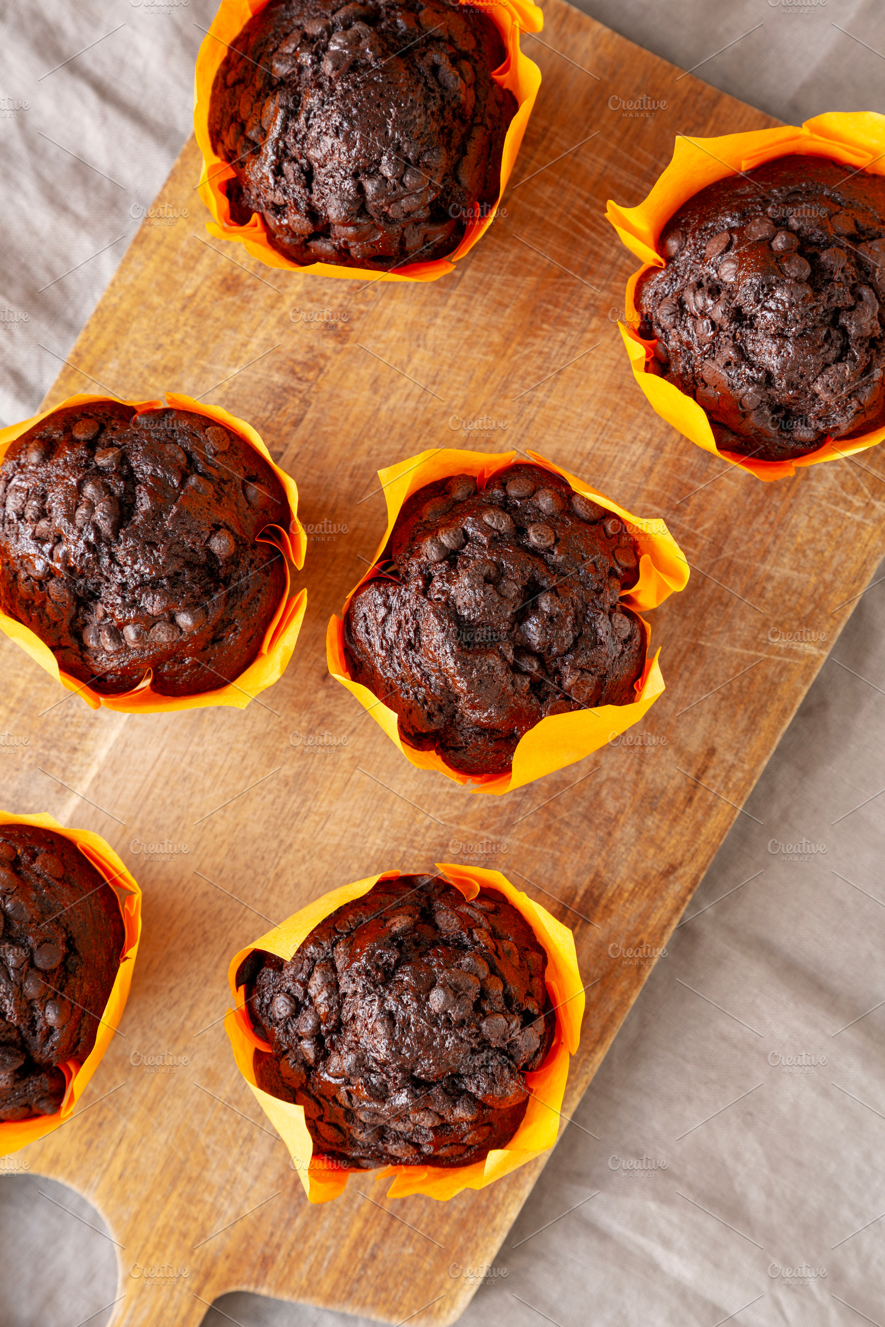 Homemade Chocolate Chip Muffins on a wooden board, top view., a Food & Drink Photo by LiudmylaChuhunova