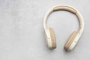 Modern wireless headphones lying on gray stone background, a Business Photo by Olena Rudo
