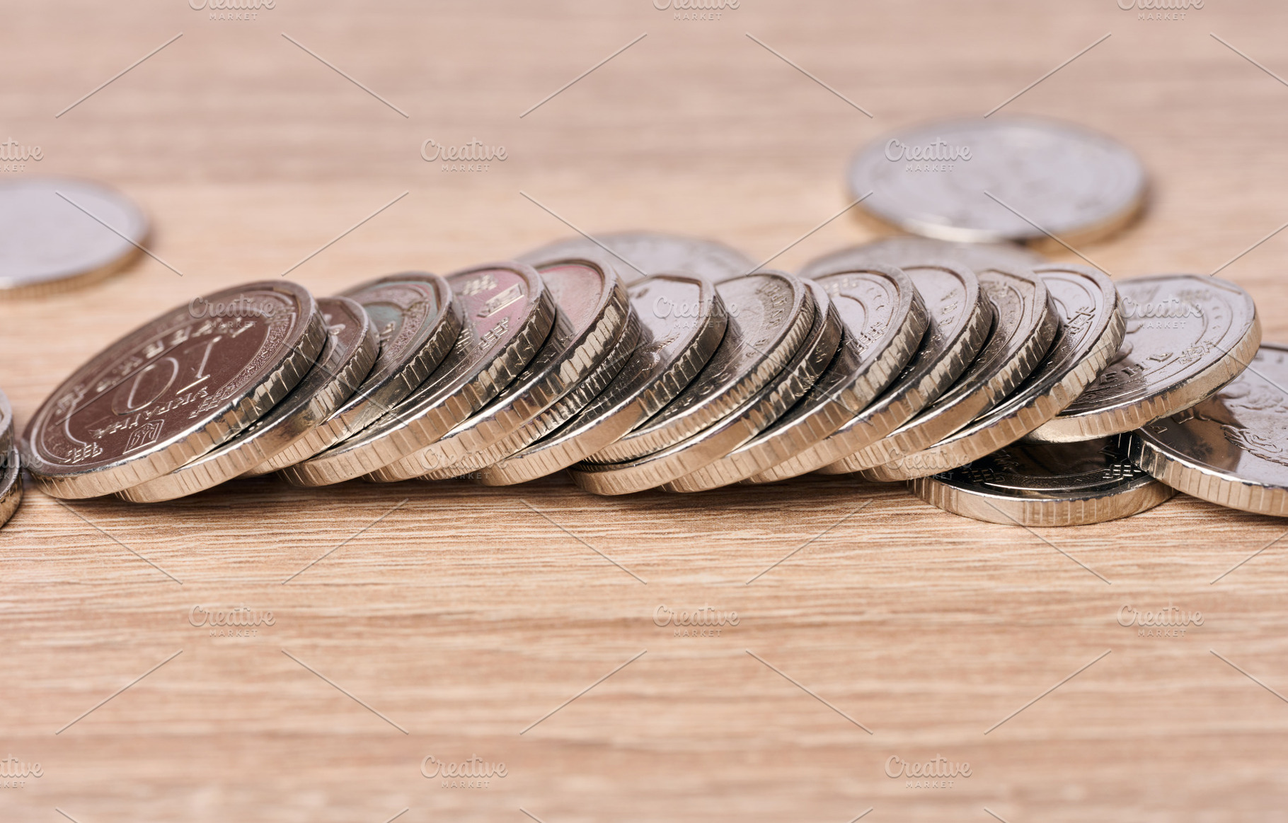 A row of Ukrainian metal coins lies on a wooden table., a Business Photo by ndanko