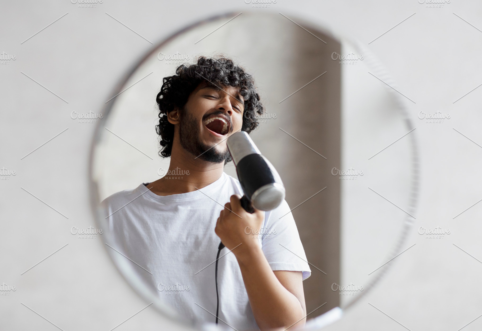 Joyful indian man having fun in the morning in bathroom, holding hairdryer and, a Person Photo by Prostock-Studio