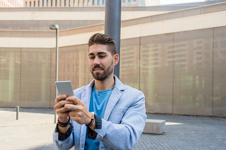 Portrait of Handsome young man smiling when he is using his mobile phone, a Person Photo by RF Images