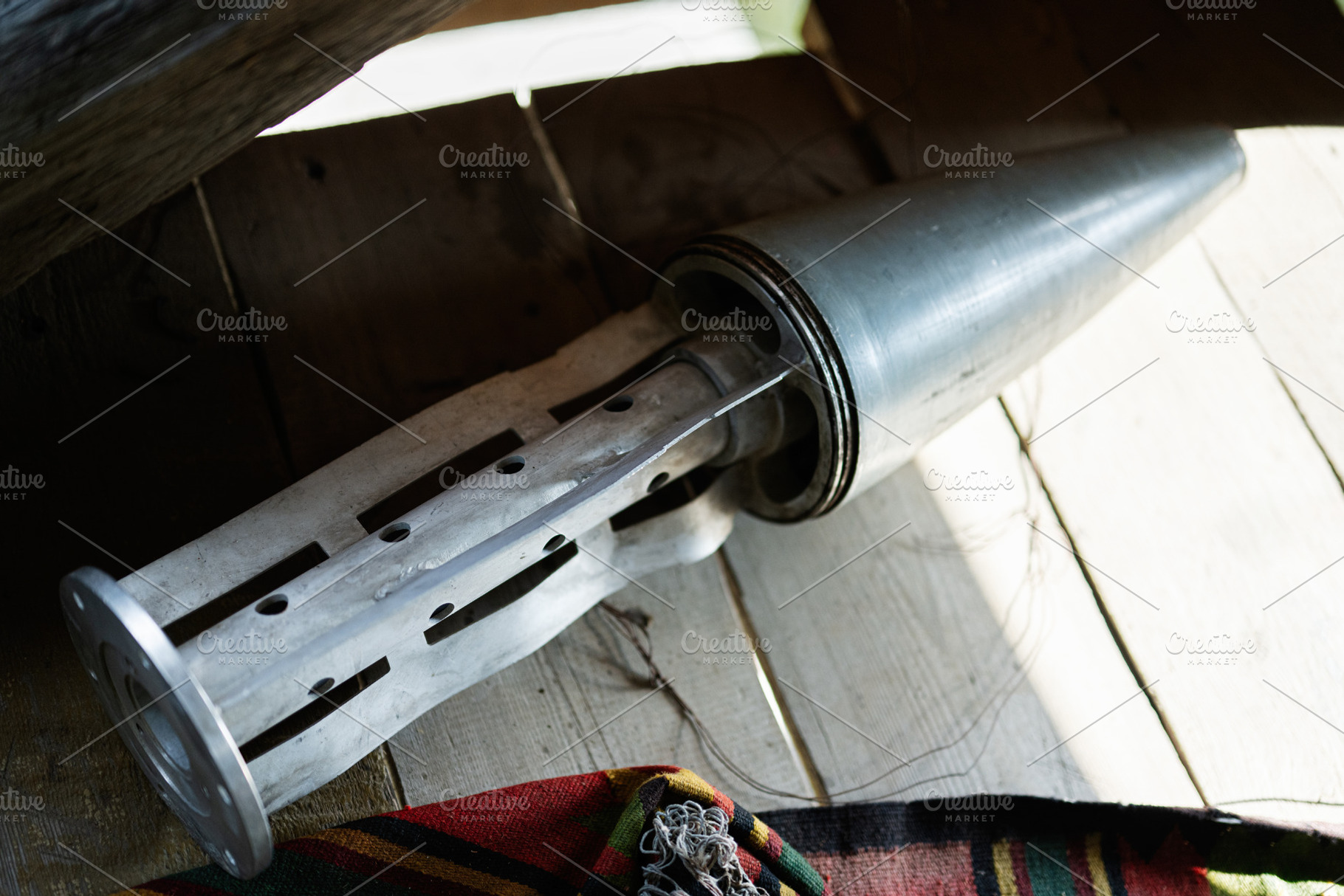 Close-up of vintage metal rocket shell component resting on wooden floor near c, a Photo by AS photostudio