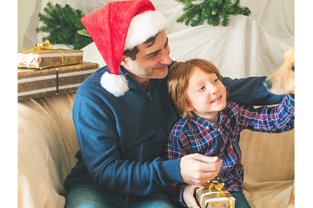 Dad and son in santa caps and dog on, a Holiday Photo by Lifemorning