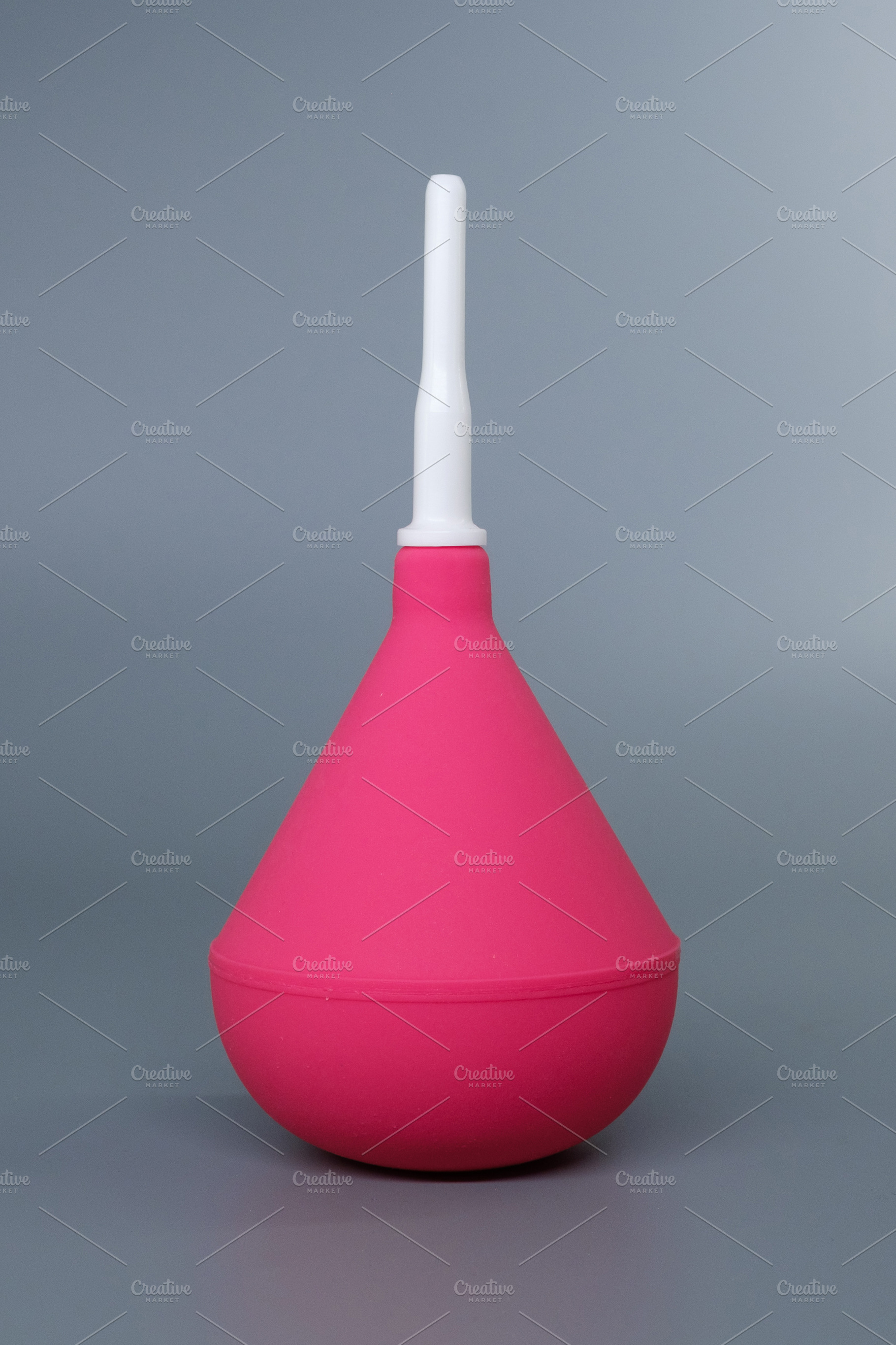 Pink medical syringe bulb with a white plastic tip on a grey background. Dispos, a Health & Medical Photo by Rohan Photography