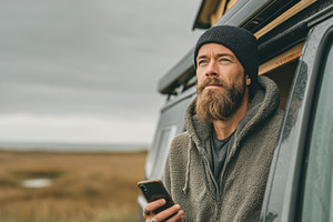 Man with phone near camper van, a Photo by Beautiful things