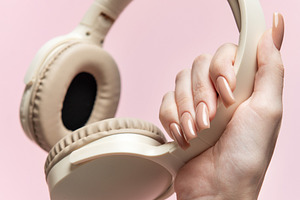 Woman holding wireless headphones on pink background, a Technology Photo by Olena Rudo
