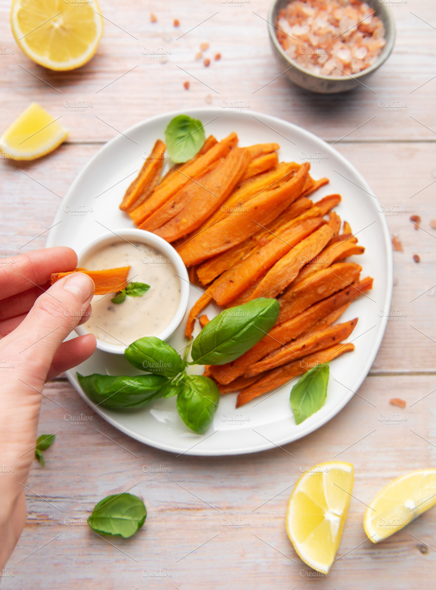 Hand dipping sweet potato fries in creamy sauce, a Food & Drink Photo by Olena Rudo