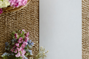 Blank white card mockup on rustic woven mat with assorted vibran, a Photo by Studio ANNA