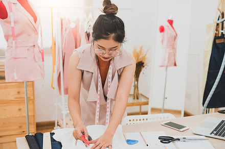 Attractive Asian female fashion designer working in home office, a Beauty & Fashion Photo by Ministocker