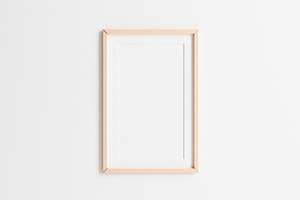 Wooden picture frame hanging on white wall background. 2:3 ratio