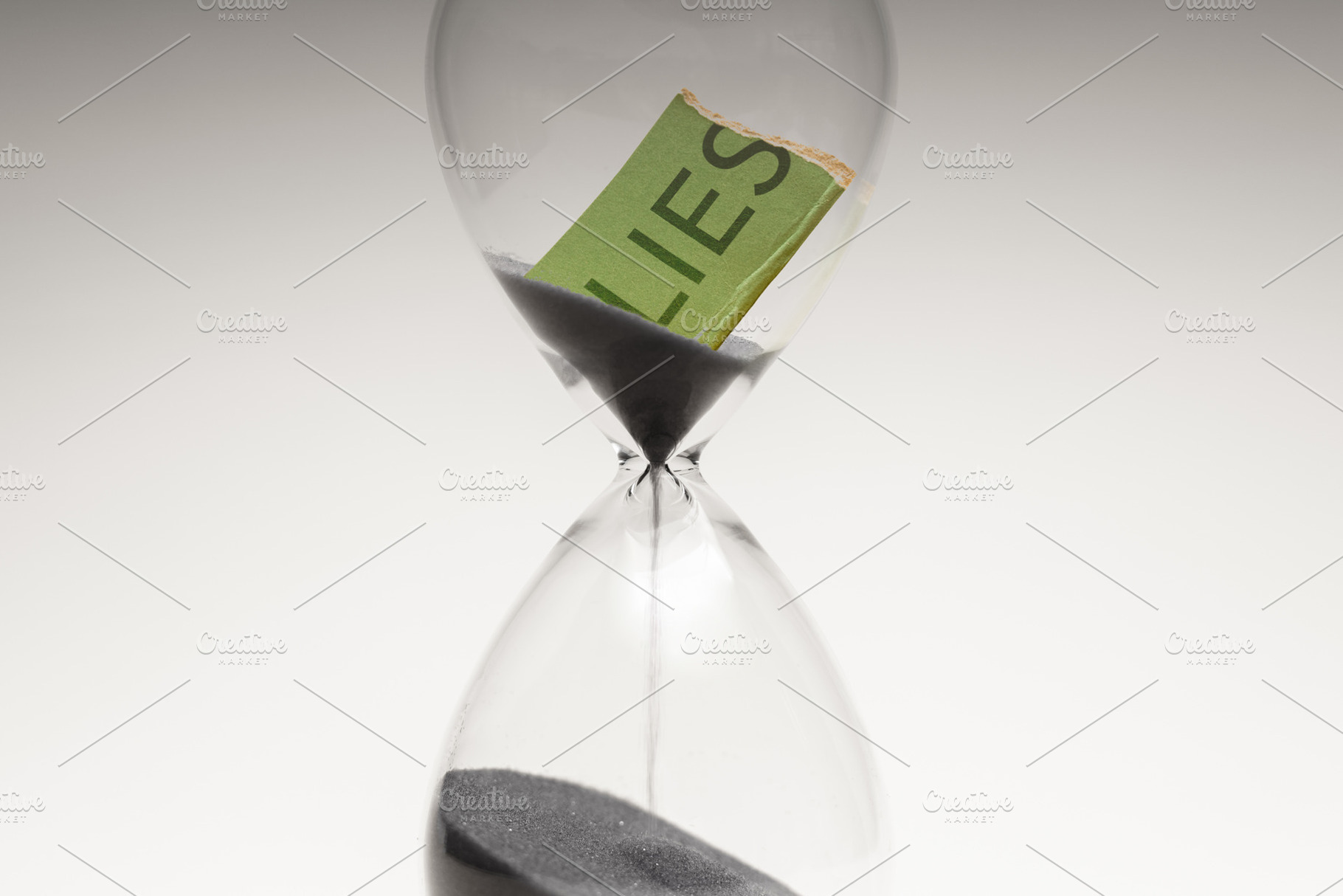 Hourglass with torn paper word LIES, deception, hidden truth and, a Photo by salmon.black
