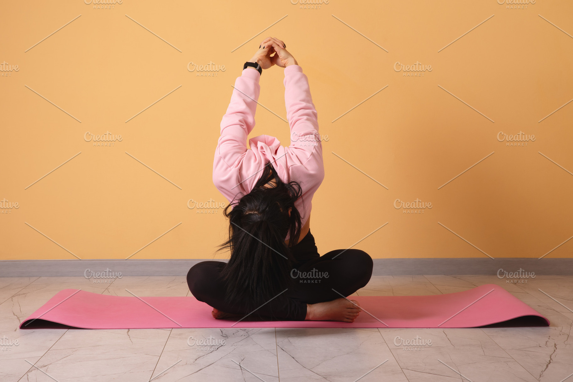 Active woman practicing a seated yoga pose on a pink mat against, a Person Photo by Ales Munt
