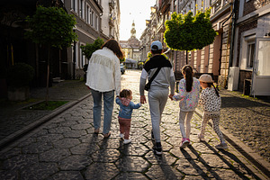Family walking together down a charming street during sunset in a historic city, a Person Photo by AS photostudio