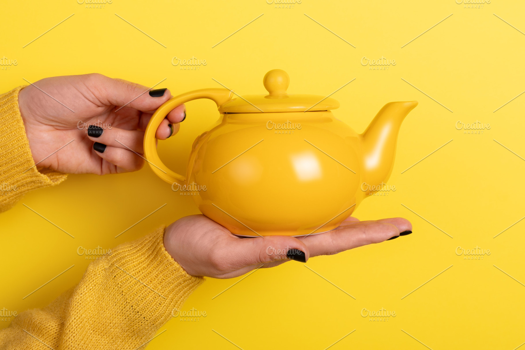 Close-up of a yellow teapot held in hands against a matching yel, a Food & Drink Photo by Ales Munt