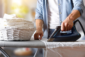 Man ironing shirt on an ironing board in living room, a Sports & Recreation Photo by Davizro's Market