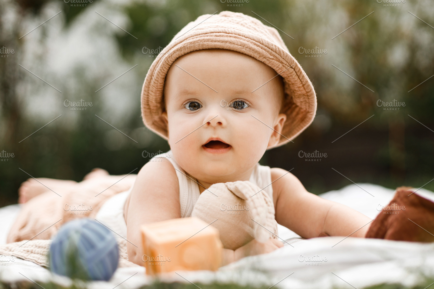 Beautiful happy baby in hat lying on blanket and playing with to, a Person Photo by Sonjachni