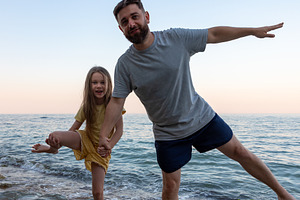 Joyful father and daughter play together at the beach, balancing on rocks near, a Person Photo by Ales Munt