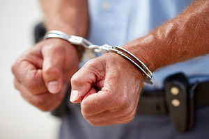 Police officer placing handcuffs on an arrested individual in a law enforcement, a Photo by AlyaAnd