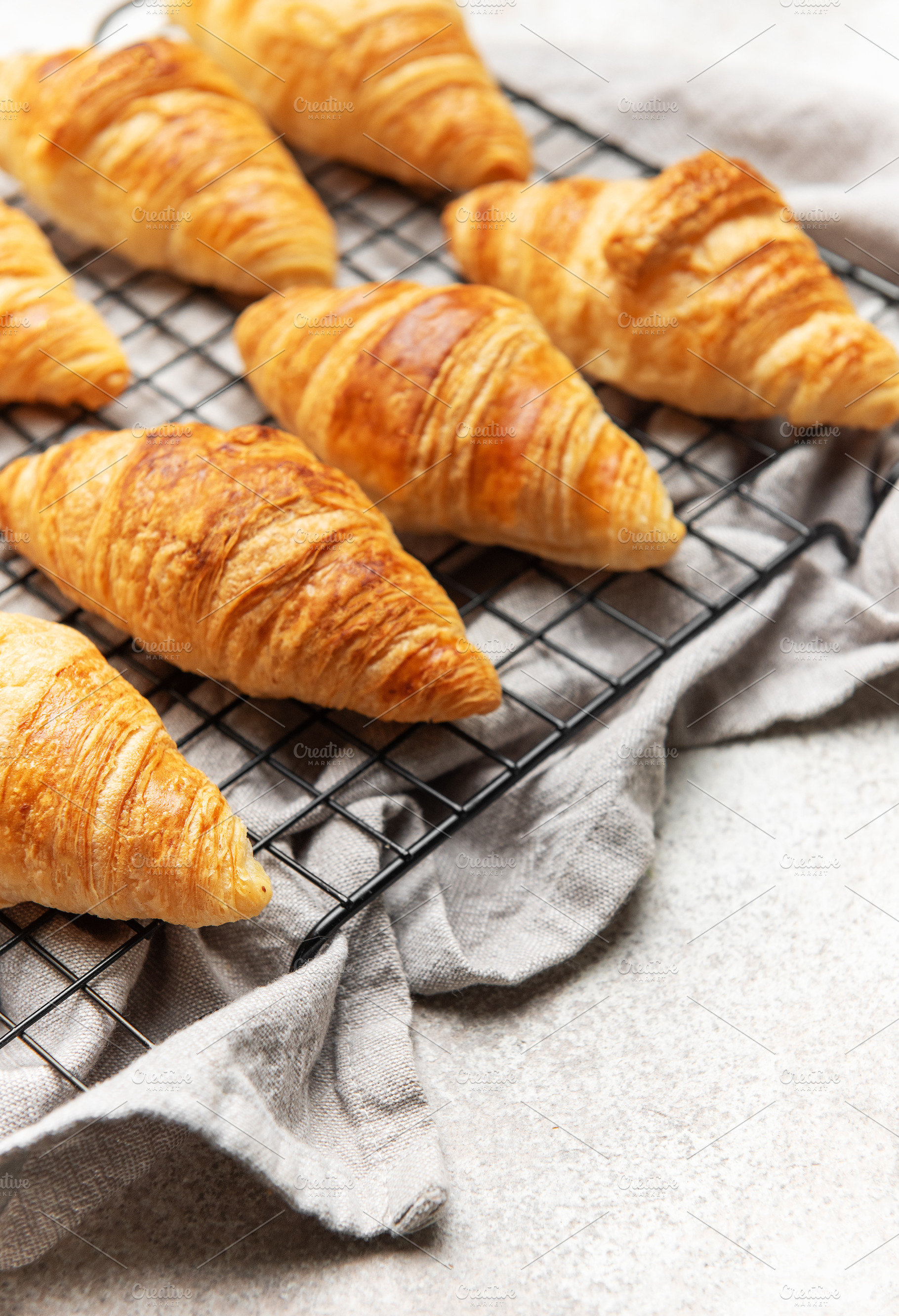 Freshly baked croissants cooling on wire rack, perfect start to, a Food & Drink Photo by Olena Rudo