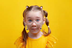 Wide-eyed girl in yellow dress wearing dangling rhinestone glass, a Person Photo by Ales Munt