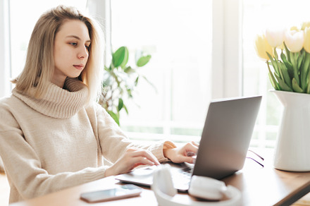 Young woman working on laptop in  home, a Person Photo by Olena Rudo