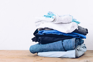Stack of clothes on table featuring iron, cloth, and laundry