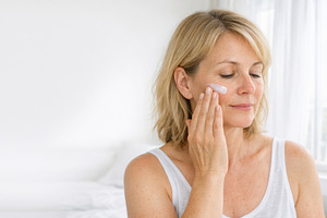 Middle-aged woman applying facial cr, a Photo by Dvoevnore photos