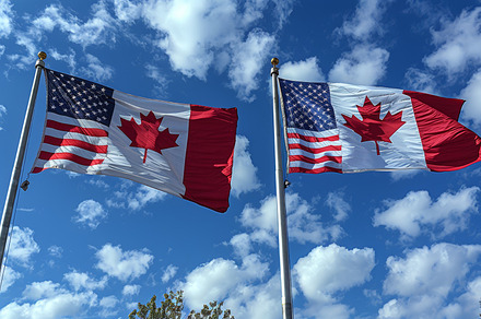 American and Canadian flags waving together under a clear blue sky, a Photo by AS photostudio