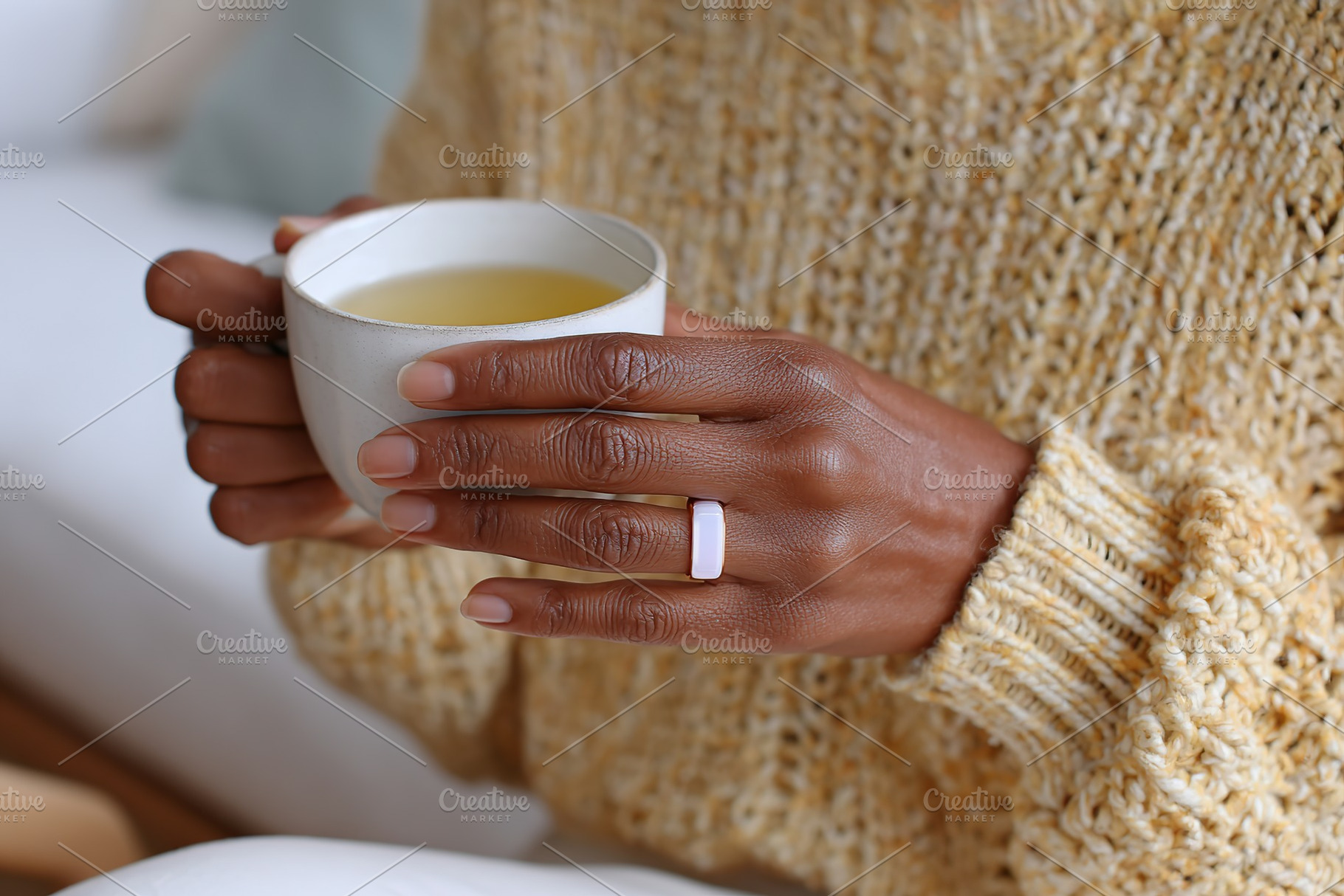 Softly glowing ring held in warm autumn light with a cup of tea, a Photo by AlyaAnd