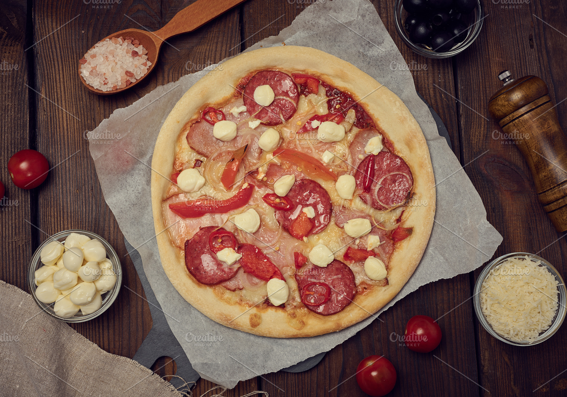 Pizza with salami, ham and mozzarella cheese on a wooden table, a Food & Drink Photo by ndanko