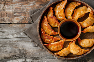 Homemade fried meat dumplings with red sauce on wooden table, a Food & Drink Photo by AlyaAnd