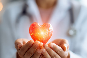 Glowing heart symbol in hands of healthcare professional, a Health & Medical Photo by AlyaAnd
