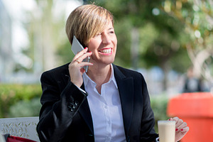 Businesswoman having coffee and phone call outdoors, a Photo by RF Images