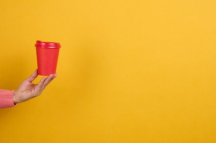 hand holds paper cardboard red cup for coffee, yellow background, a Food & Drink Photo by ndanko