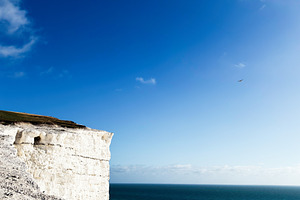 Cliffs at Seven Sisters in East Sussex overlook the sea under a clear blue sky, a Nature Photo by AS photostudio