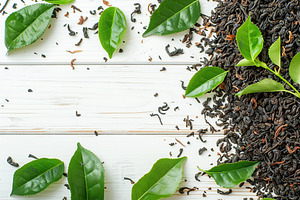 Dry tea leaves with fresh green tea leafs and copyspace on wooden background, a Food & Drink Photo by AlyaAnd