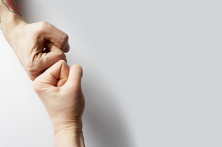 Close up clash of two fists on white